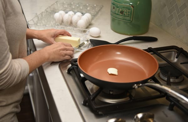 woman placing butter in frying pan