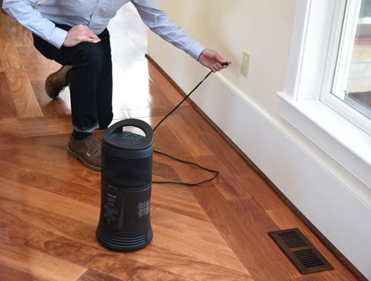 man plugging portable heater into electrical outlet