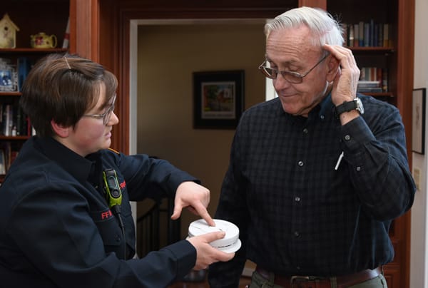 firefighter testing a smoke alarm for an older adult