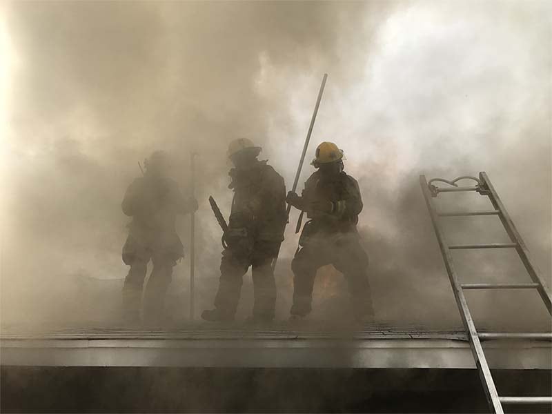 3 firefighters on a smokey roof