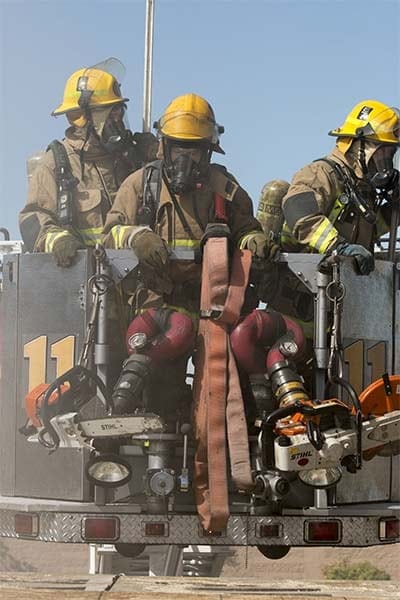 3 firefighters on a ladder apparatus